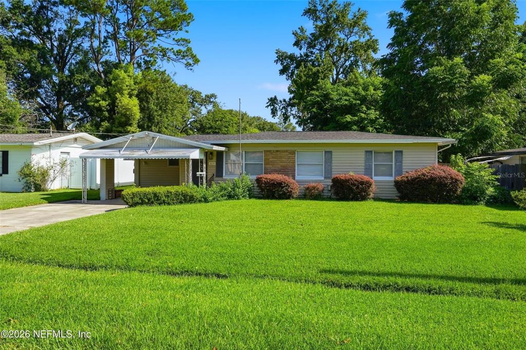 A single-story house with a carport and a large front lawn under a blue sky — 5239 GLENWOOD AVENUE, JACKSONVILLE, FL