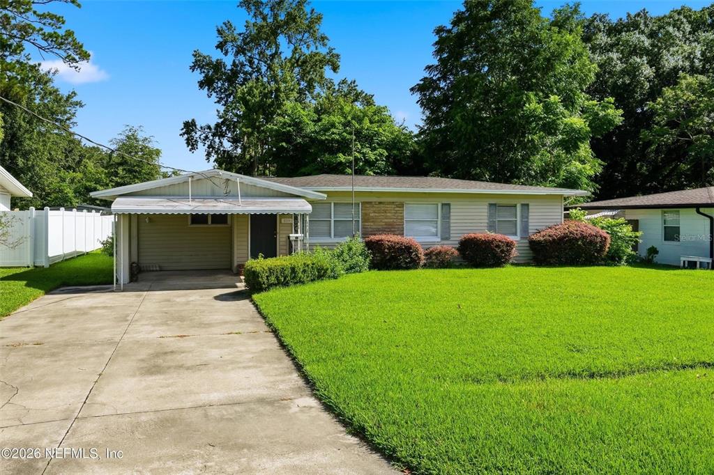 A single-story house with a carport, light siding, and a large front lawn — 5239 GLENWOOD AVENUE, JACKSONVILLE, FL