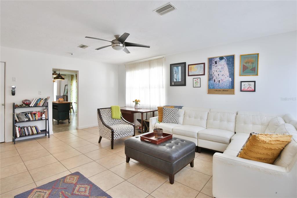 A living room features a white sectional sofa, a dark ottoman, and tiled flooring — 1138 47TH STREET, SARASOTA, FL