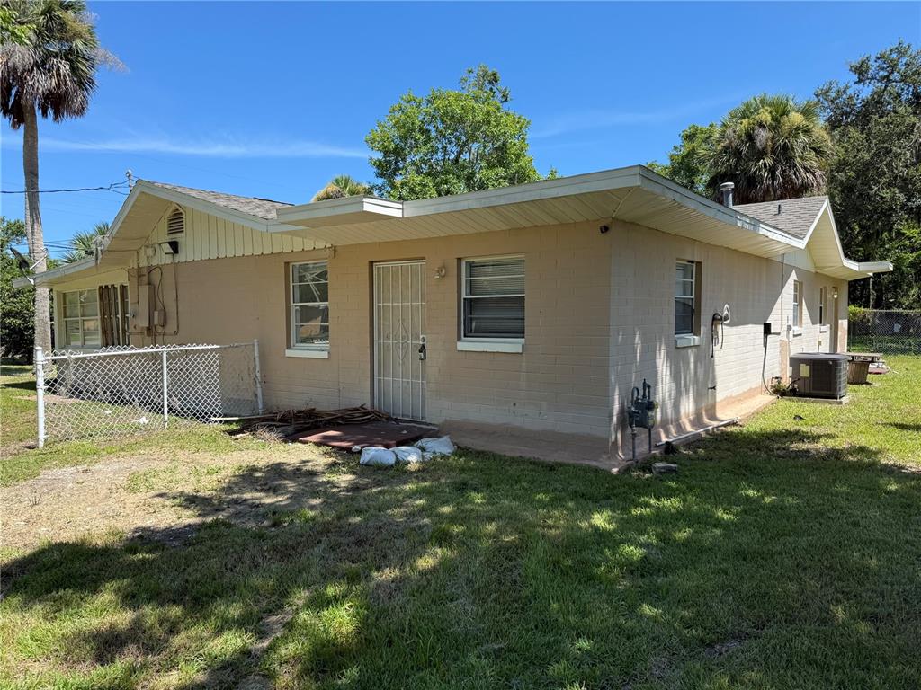 A single-story tan brick house features a white security door and a chain-link fence — 416 S CAROLINE STREET, DAYTONA BEACH, FL