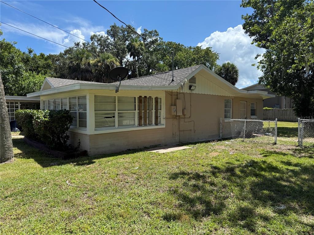 The exterior of a single-story house with a tan stucco finish and a fenced yard — 416 S CAROLINE STREET, DAYTONA BEACH, FL