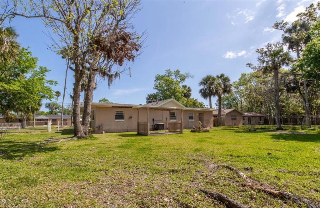 A single-story house with a covered patio sits on a large, grassy, tree-filled lot — 416 S CAROLINE STREET, DAYTONA BEACH, FL