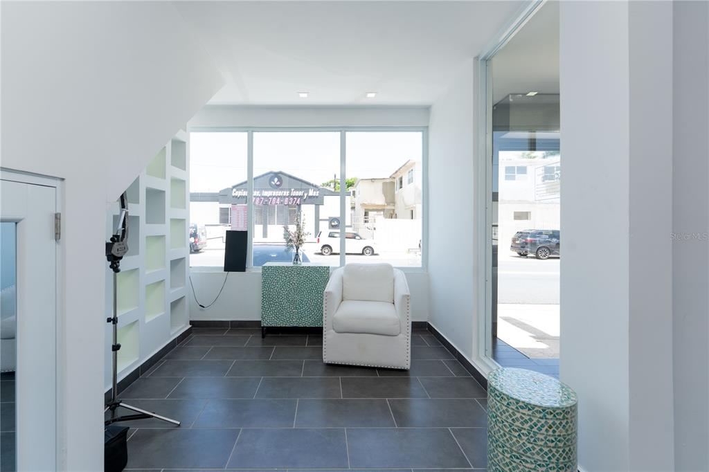 A bright room with dark tile floors, a white armchair, and large windows facing outdoors — 1400 AMERICO MIRANDA AVENUE, SAN JUAN, PR
