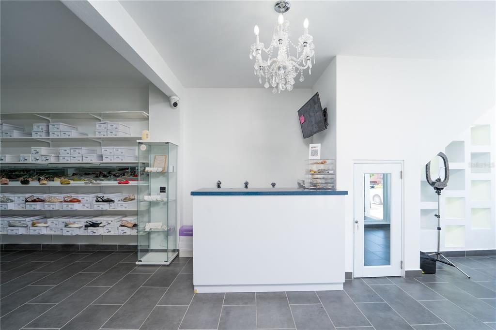 A retail reception area features a white counter, a crystal chandelier, and wall-mounted shoe shelving — 1400 AMERICO MIRANDA AVENUE, SAN JUAN, PR