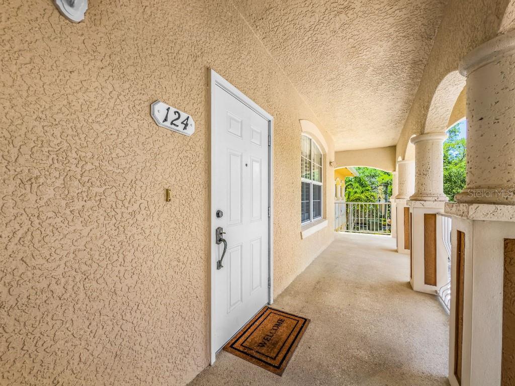 A white front door with number 124 is located on a covered outdoor balcony — 3314 WOOD THRUSH DRIVE UNIT 124, PUNTA GORDA, FL