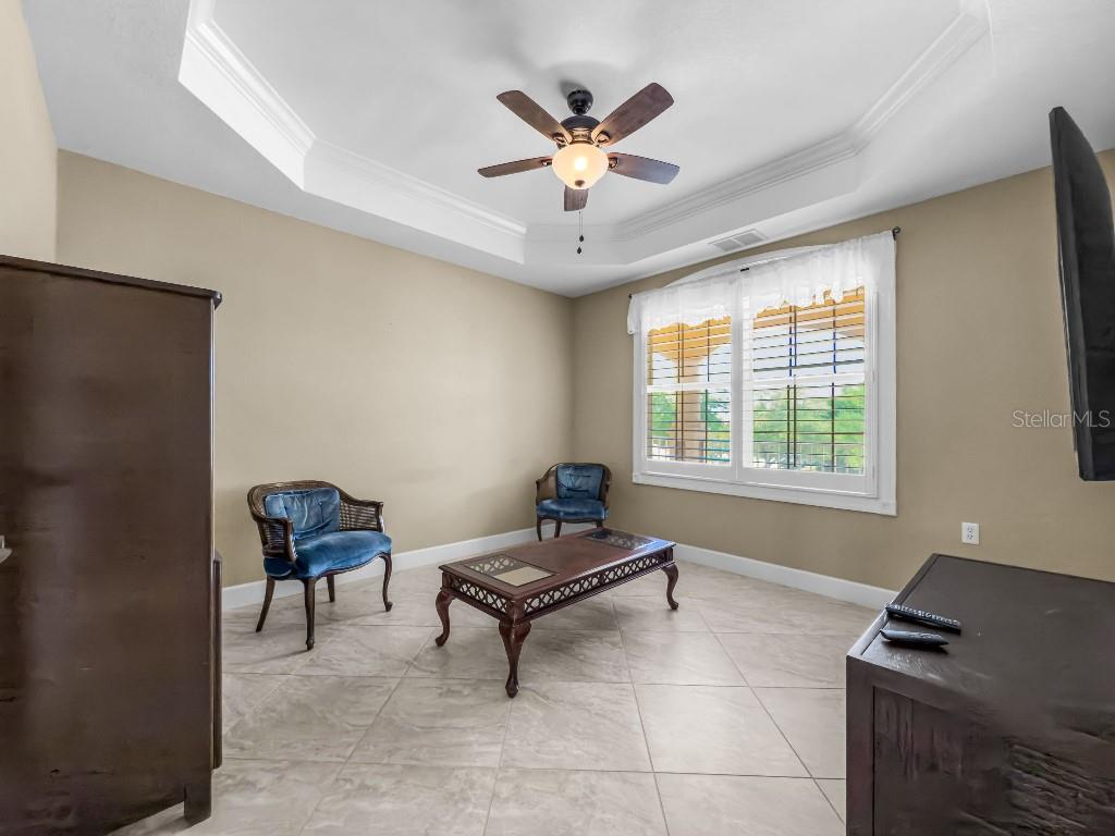 A living room features tile flooring, a tray ceiling with a fan, and two blue chairs — 3314 WOOD THRUSH DRIVE UNIT 124, PUNTA GORDA, FL