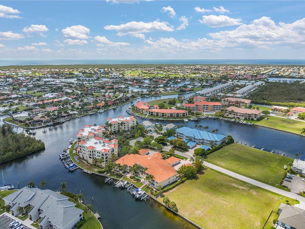 An aerial view of waterfront residential buildings and canals surrounded by a suburban landscape — 3314 WOOD THRUSH DRIVE UNIT 124, PUNTA GORDA, FL