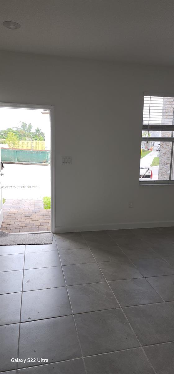 A room with gray tile flooring features an open doorway and a window — 12113 NW 23rd Court, Miami FL 33167, MIAMI, FL