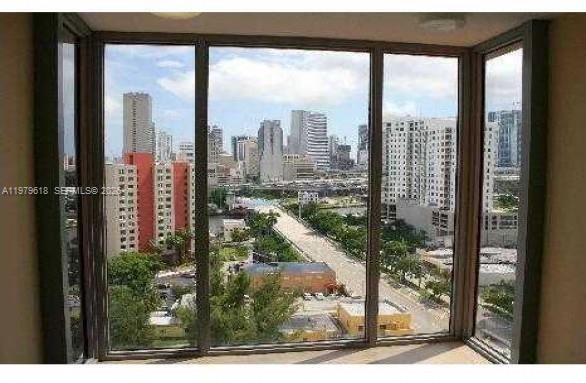 A view of a city skyline seen through large floor-to-ceiling windows in a room — 36 NW 6th Ave # 801, Miami FL 33128, MIAMI, FL