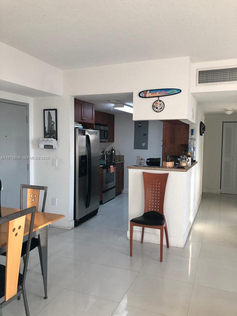 A kitchen with stainless steel appliances and wood cabinets opens to a dining area — 36 NW 6th Ave # 801, Miami FL 33128, MIAMI, FL