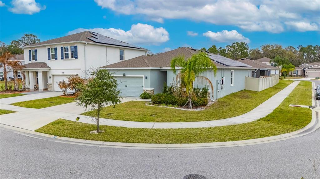 A two-story house and a single-story house with solar panels sit on a corner lot — 33146 SAND CREEK DRIVE, WESLEY CHAPEL, FL