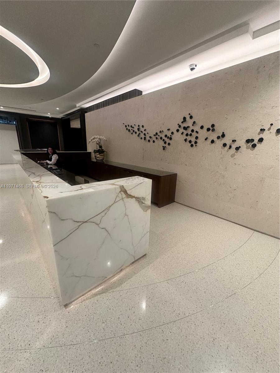 A modern kitchen features white cabinetry, a dark granite island, and a large abstract painting — 1717 N Bayshore Dr # 2740, Miami FL 33132, MIAMI, FL