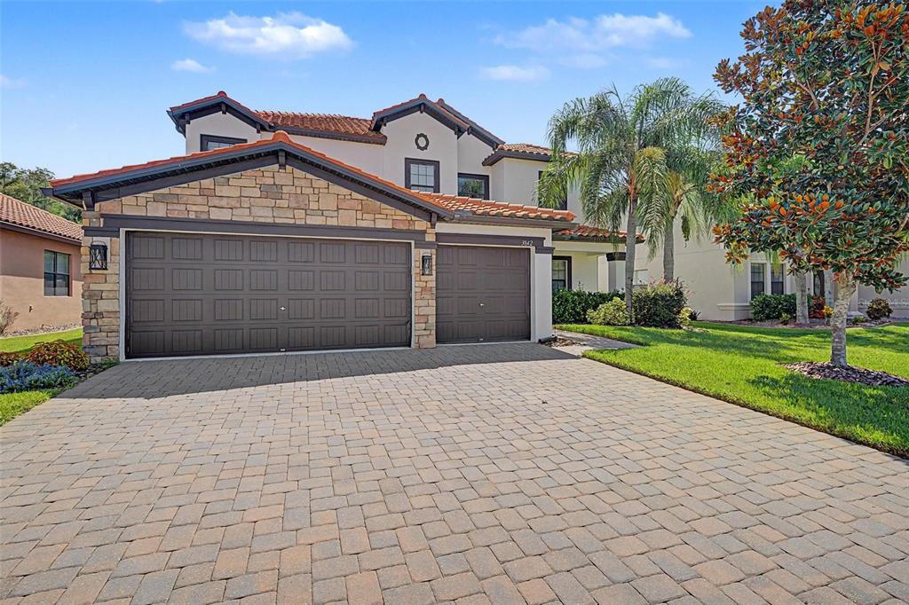 A two-story house with a stone-accented facade, a paver driveway, and a three-car garage — 3842 WELLINGBOROUGH COURT, LAND O LAKES, FL