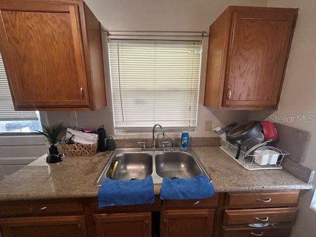 A kitchen sink area features wooden cabinets, a window with blinds, and a granite countertop — 399 BETH DRIVE, SANFORD, FL