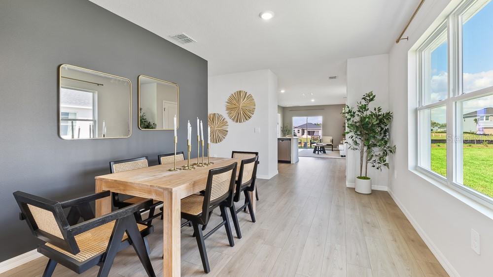 A dining room with a wooden table, black chairs, and a gray accent wall — 1825 HAMMOCK TRACE DRIVE, PARRISH, FL