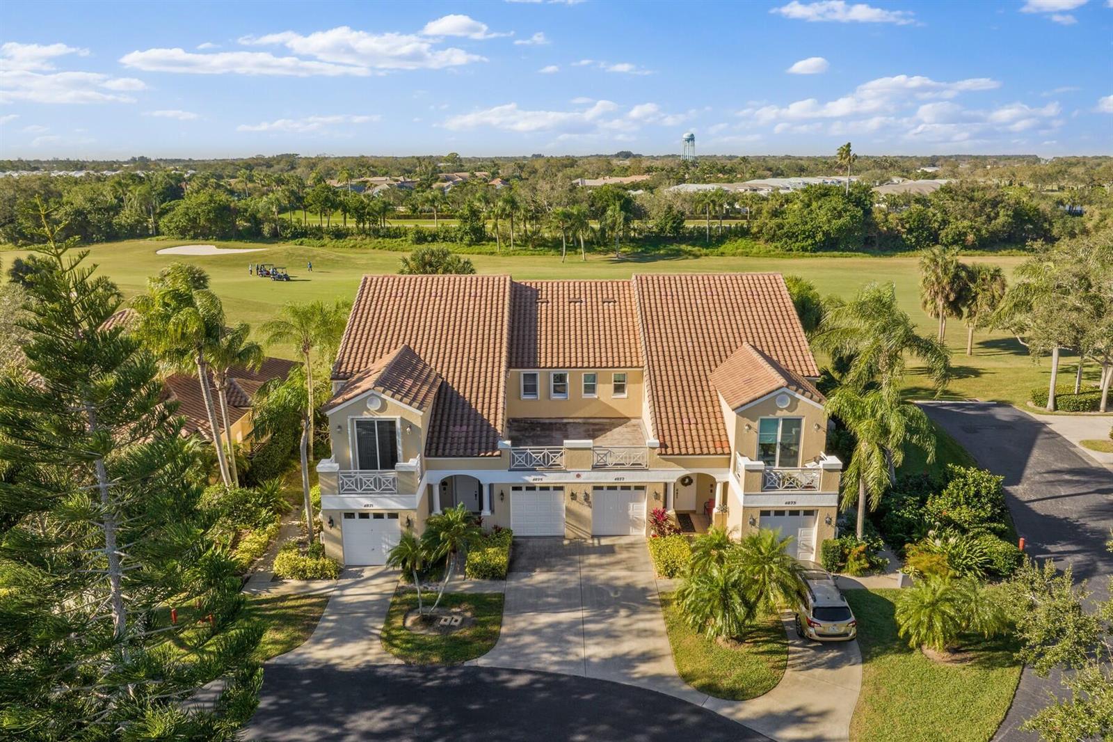An aerial view of a two-story duplex with a tile roof overlooking a golf course — VERO BEACH, FL