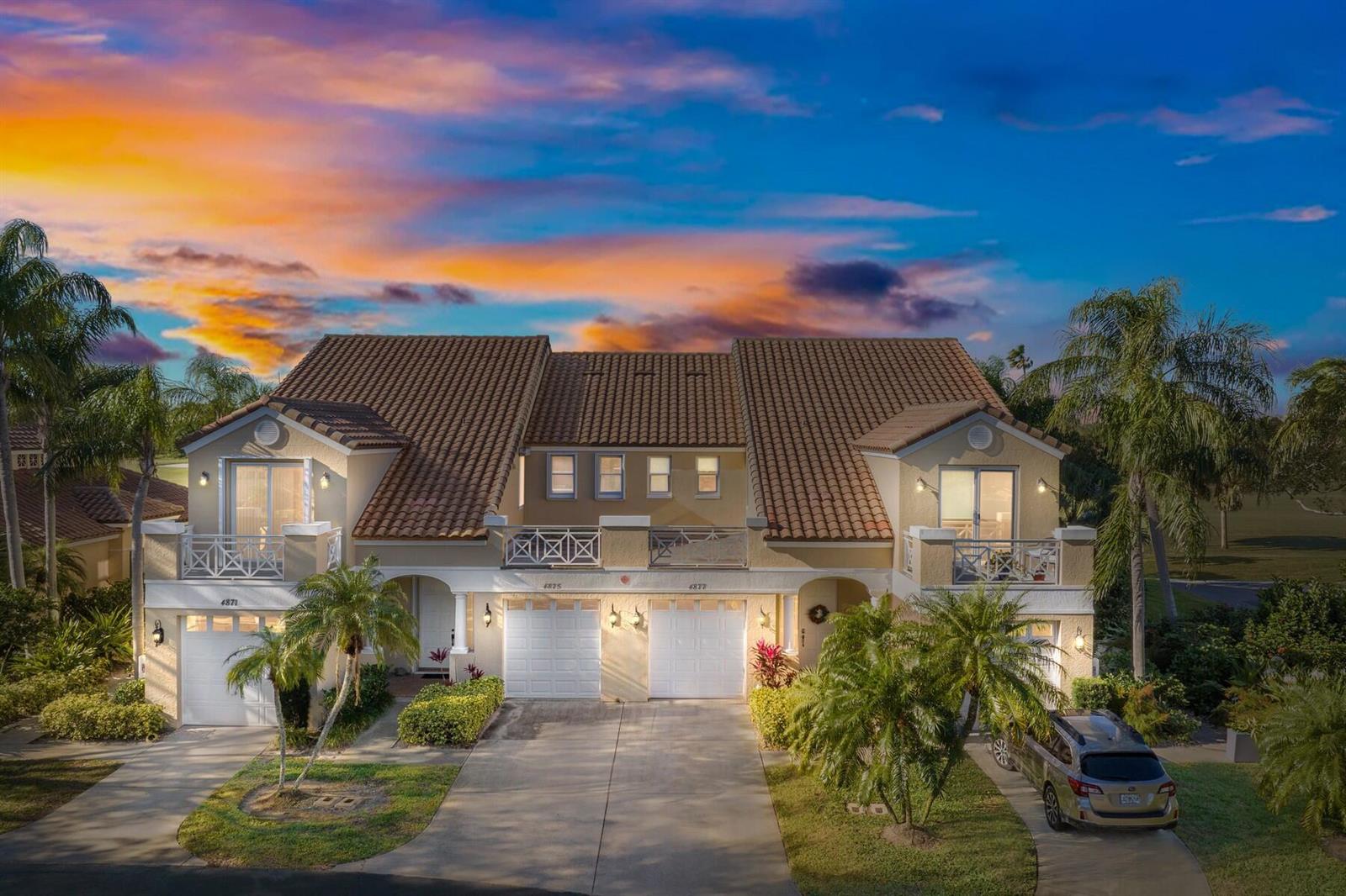 An exterior view of a multi-unit residential building with tile roofs and attached garages — VERO BEACH, FL
