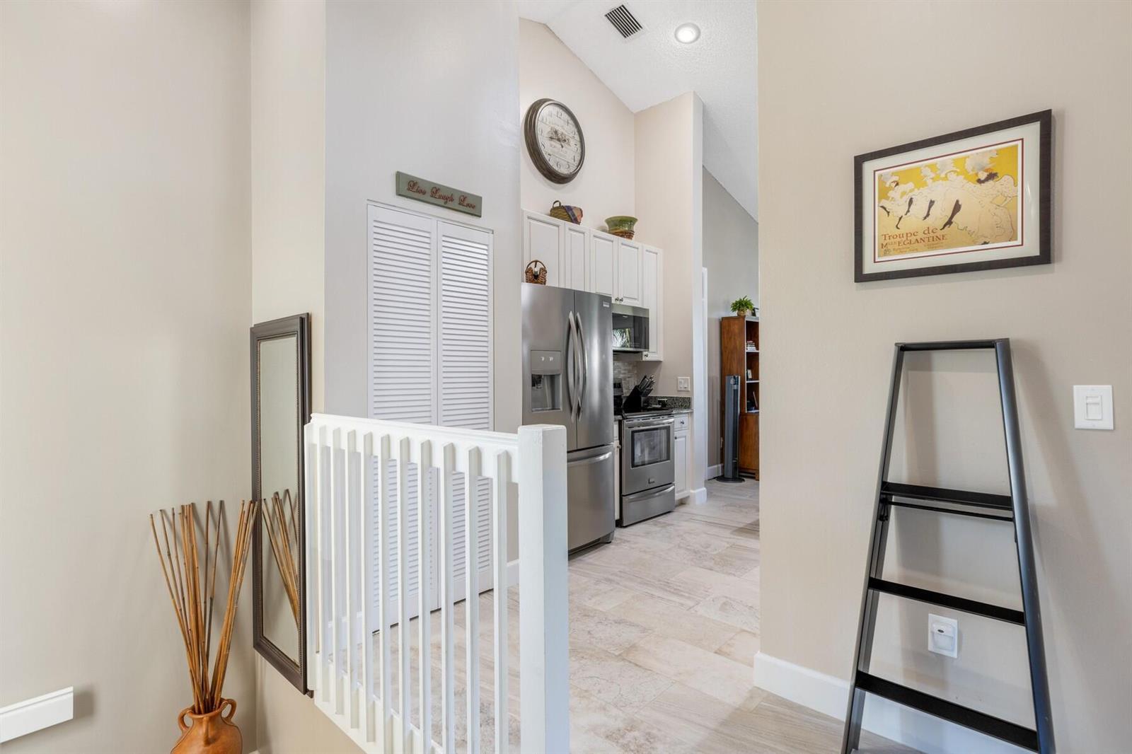 A view from a hallway looking into a kitchen with stainless steel appliances and cabinetry — VERO BEACH, FL
