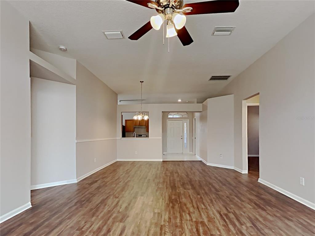 An open living area with wood-look flooring, a ceiling fan, and a kitchen pass-through window — 12306 TWINKLING STAR PLACE, RIVERVIEW, FL