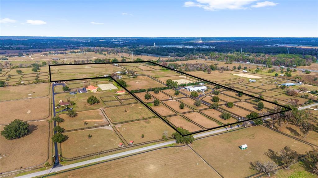 An aerial view shows a large fenced horse farm with multiple paddocks and several buildings — 5575 NW 100TH STREET, OCALA, FL