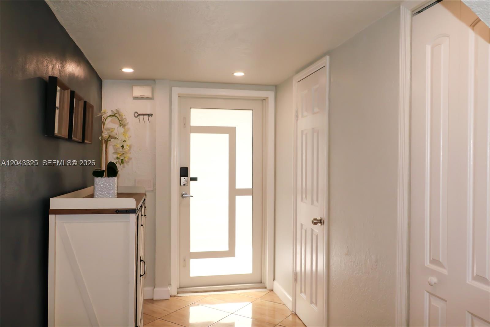 An entryway features a white door with geometric glass panels, tile flooring, and a cabinet — 400 NW 107th Ave # 10C, Miami FL 33172, MIAMI, FL