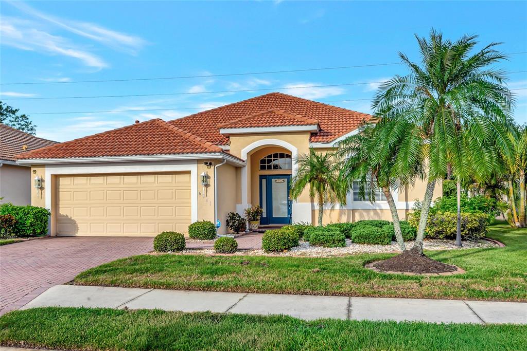 A single-story house with a tiled roof, a two-car garage, and a palm tree — 6841 74TH STREET CIRCLE E, BRADENTON, FL