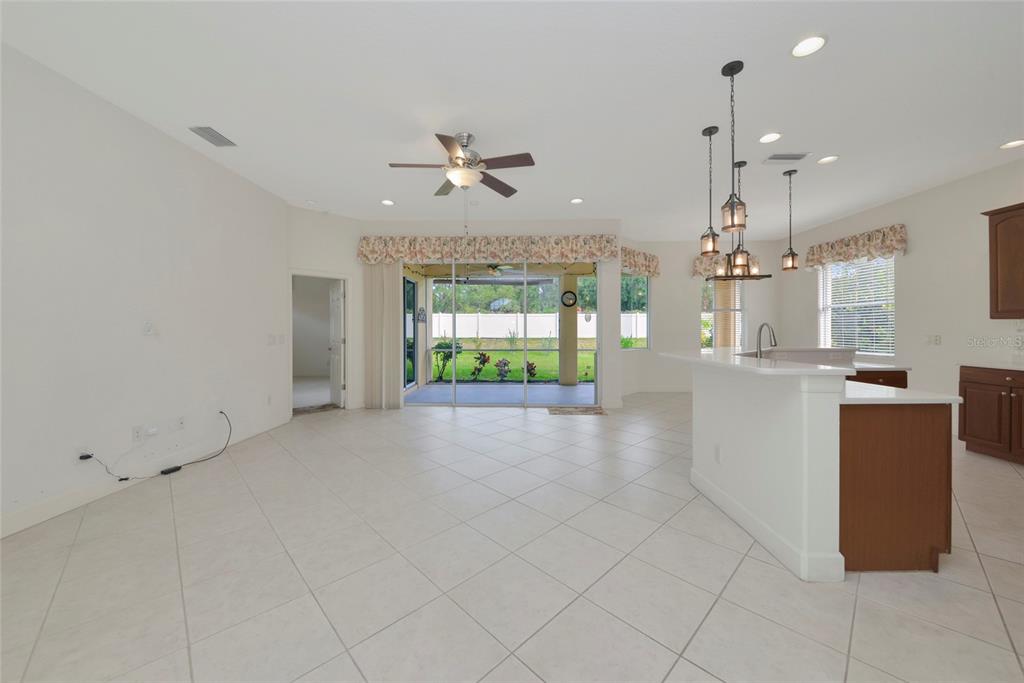 An open-concept living and kitchen area features tile flooring, a ceiling fan, and sliding doors — 6841 74TH STREET CIRCLE E, BRADENTON, FL