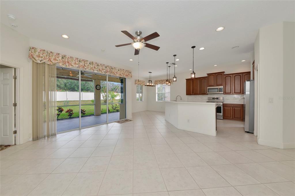 An open-concept kitchen and living area features tile flooring, wood cabinetry, and sliding glass doors — 6841 74TH STREET CIRCLE E, BRADENTON, FL
