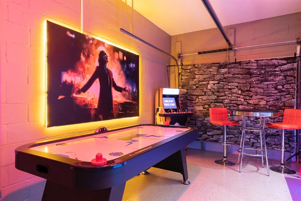 A game room features an air hockey table, a Joker wall art piece, and bar seating — 3004 PROTAGONIST STREET, KISSIMMEE, FL