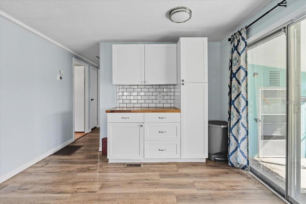 A kitchen area features white cabinets, a wood countertop, and a white subway tile backsplash — 8188 ROBERT STREET, ENGLEWOOD, FL