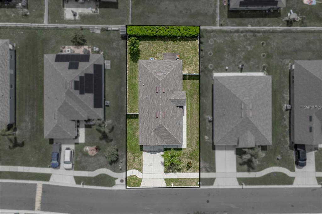 This aerial view shows a single-family home with a fenced backyard and driveway — 7552 JENO STREET, ZEPHYRHILLS, FL