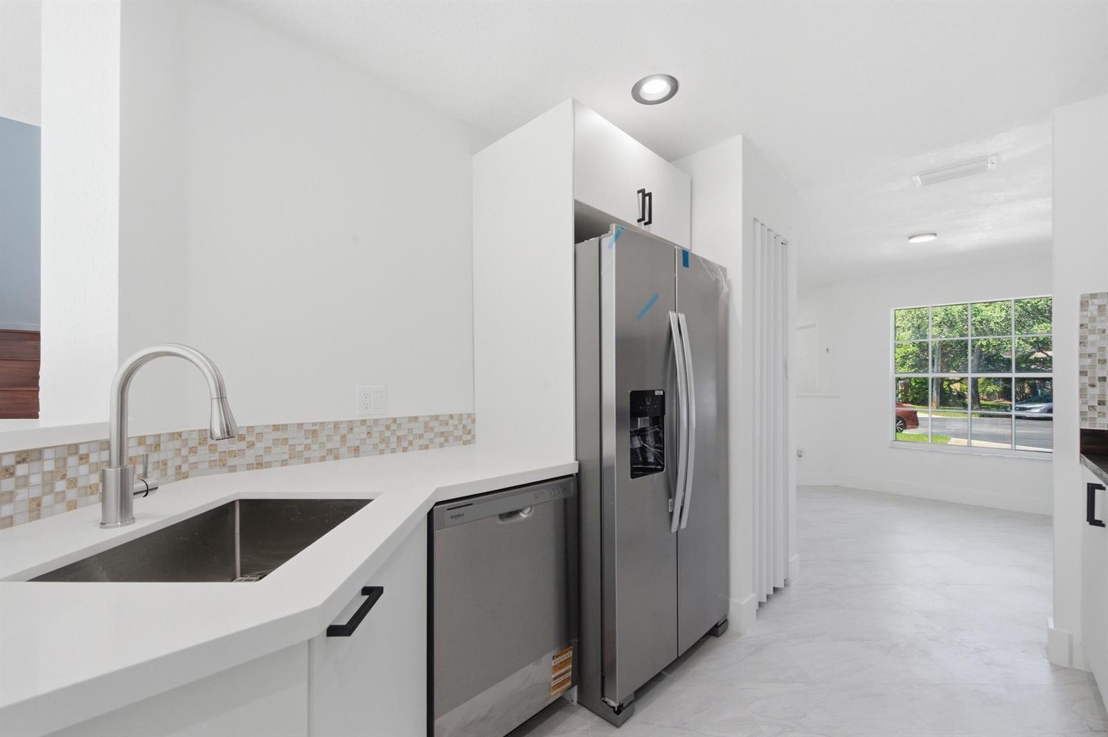 A kitchen features white cabinets, stainless steel appliances, a sink, and a tiled backsplash — 2824 NW 99th Terrace, Sunrise FL 33322, SUNRISE, FL