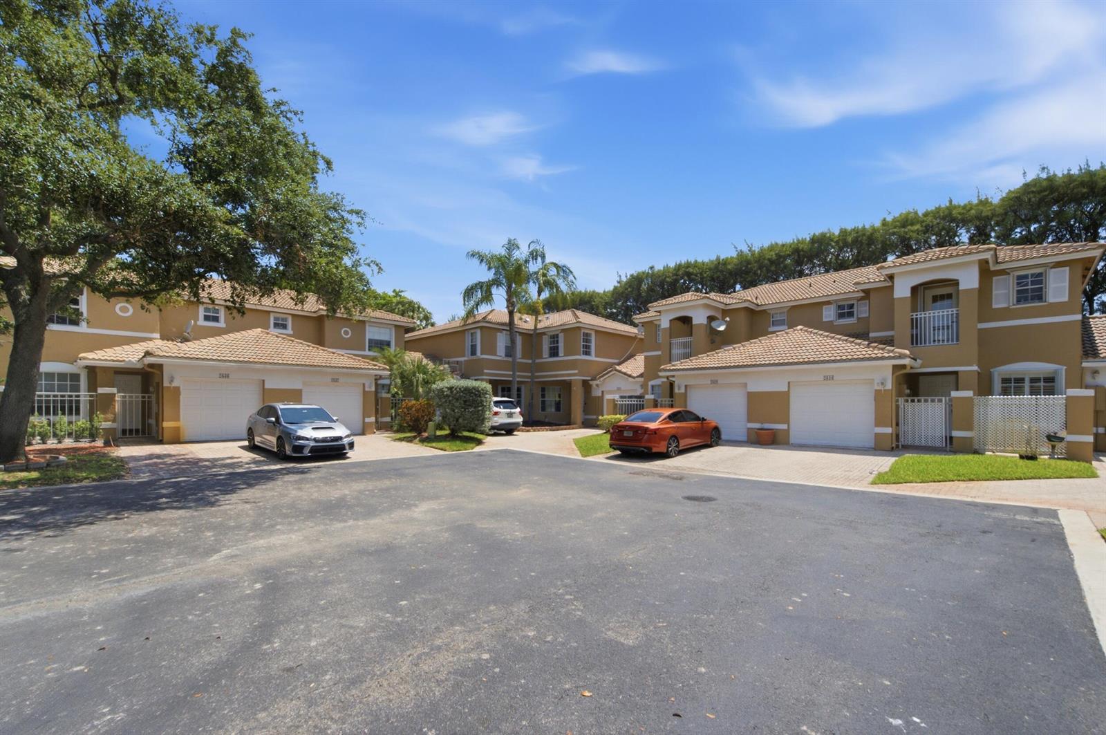 A view of a residential complex with tan townhouses, garages, and parked cars — 2824 NW 99th Terrace, Sunrise FL 33322, SUNRISE, FL