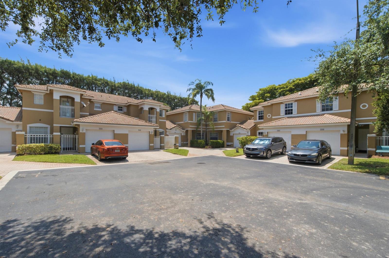 A view of the exterior of two-story townhomes with garages and parked cars — 2824 NW 99th Terrace, Sunrise FL 33322, SUNRISE, FL