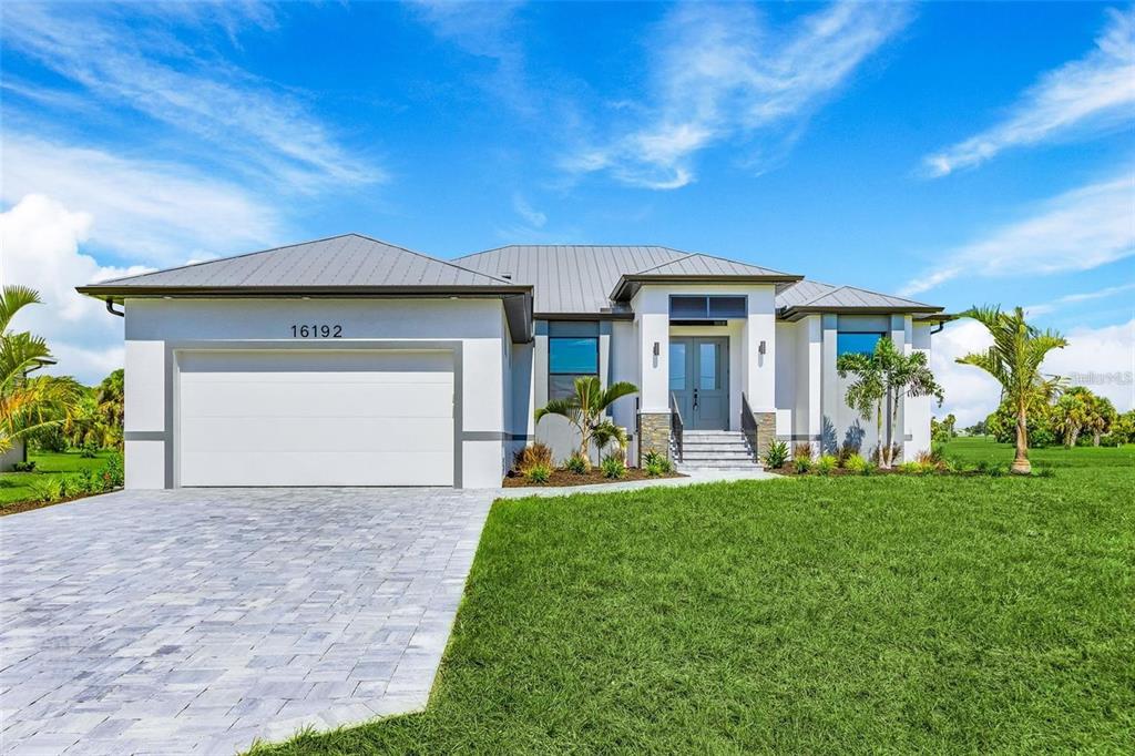 A modern single-story house with a metal roof, white stucco exterior, and a paved driveway — 17149 SARONG LANE, PUNTA GORDA, FL