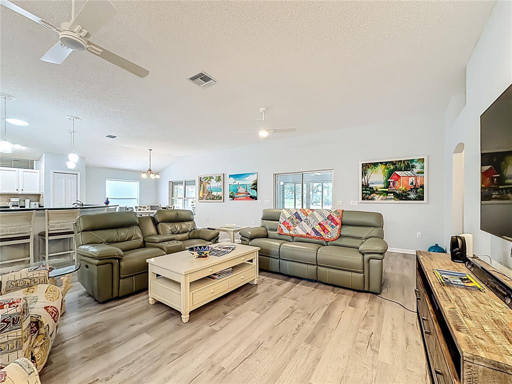 A living room with light wood-look flooring, two sage green sofas, and a coffee table — 1738 AUGUSTINE DRIVE, THE VILLAGES, FL