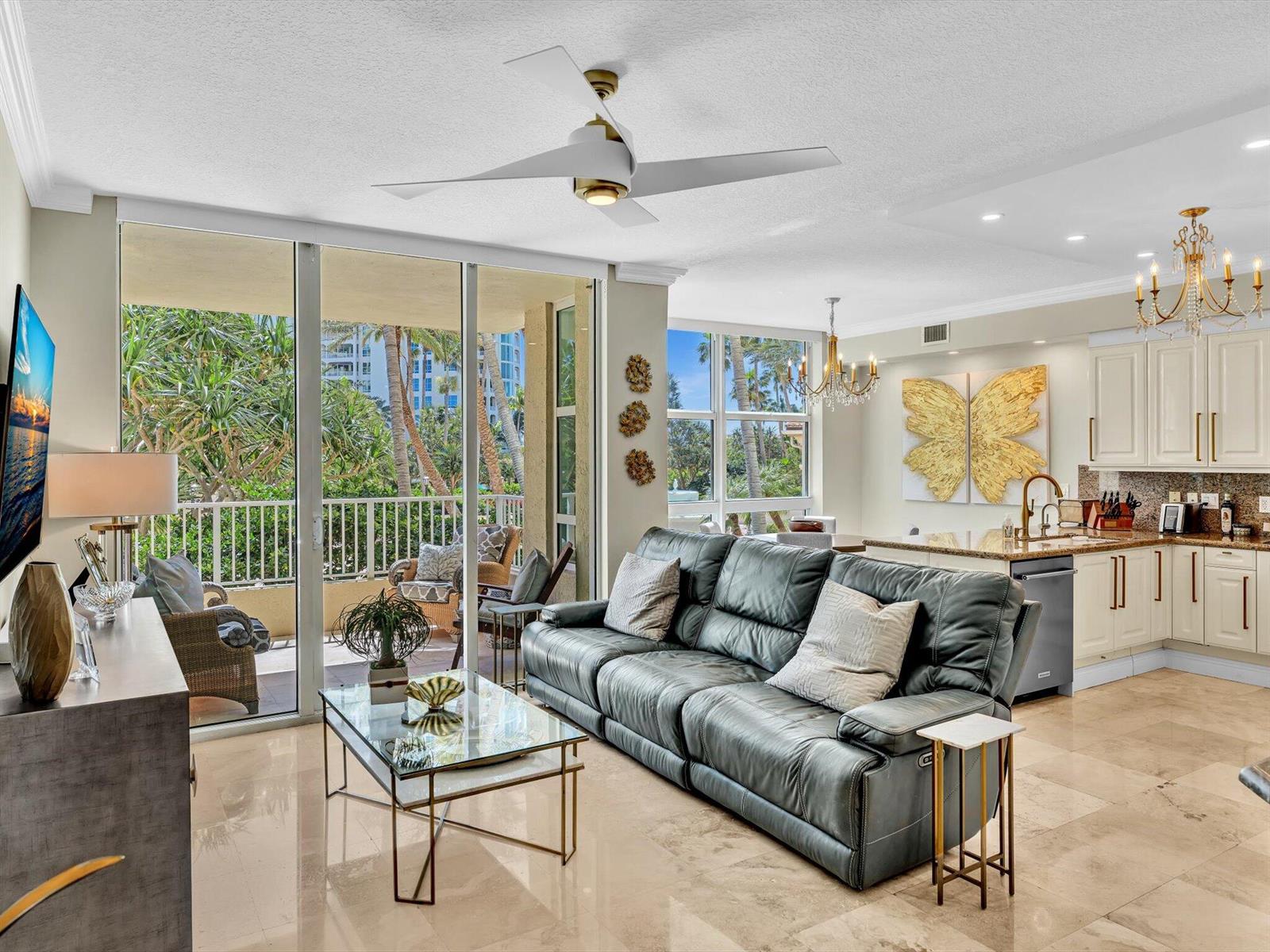 A living room with a grey leather sofa, glass coffee table, and balcony access — 3720 S Ocean Boulevard # 207, Highland Beach FL 33487, HIGHLAND BEACH, FL