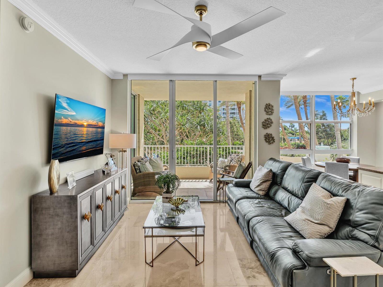 A living room features a dark leather sofa, a glass coffee table, and a balcony view — 3720 S Ocean Boulevard # 207, Highland Beach FL 33487, HIGHLAND BEACH, FL