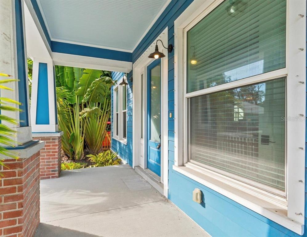 A blue-sided house features a covered front porch with a brick pillar and glass door — 214 E FLORIBRASKA AVENUE, TAMPA, FL