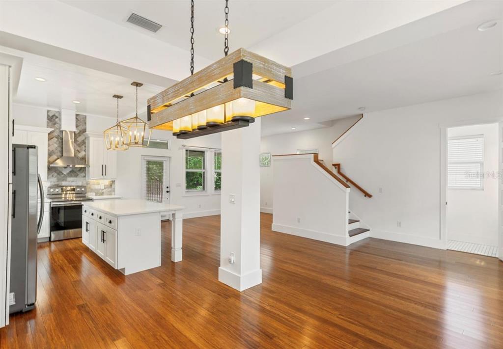 A kitchen with a large island and wooden floors opens into a living area with stairs — 214 E FLORIBRASKA AVENUE, TAMPA, FL