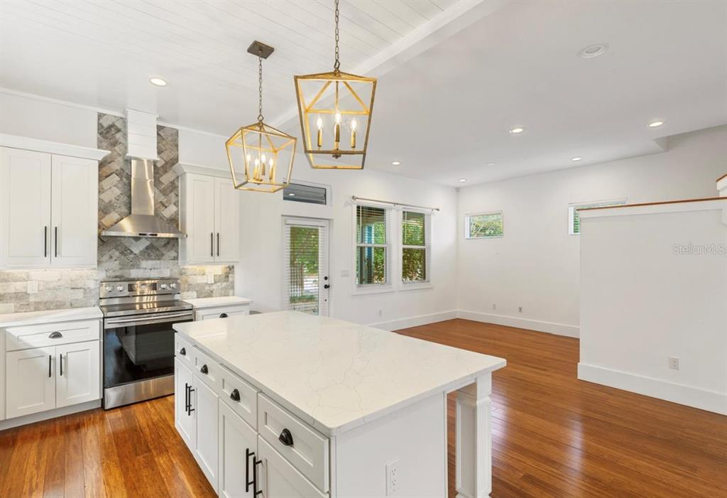 A kitchen with white cabinets, a stone backsplash, and a large island with pendant lights — 214 E FLORIBRASKA AVENUE, TAMPA, FL