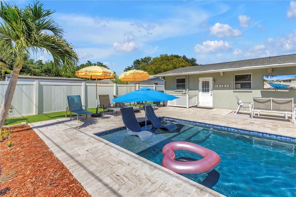 A backyard swimming pool with lounge chairs, umbrellas, and a pink float on a patio — 12096 OAK STREET, LARGO, FL