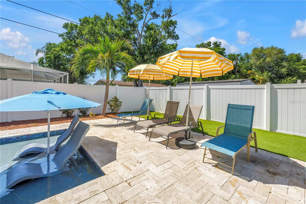 A backyard patio features a small pool, lounge chairs, and yellow-striped umbrellas — 12096 OAK STREET, LARGO, FL