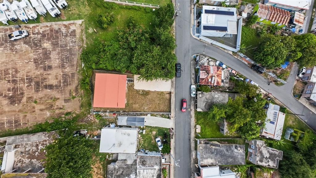 An aerial view shows a residential street with houses, a vacant lot, and parked vehicles — . TABLAZO UNIT 507, FAJARDO, PR