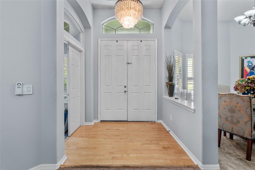 An entryway features a double front door, light wood flooring, and a decorative chandelier — 1381 SHELTER ROCK ROAD, ORLANDO, FL
