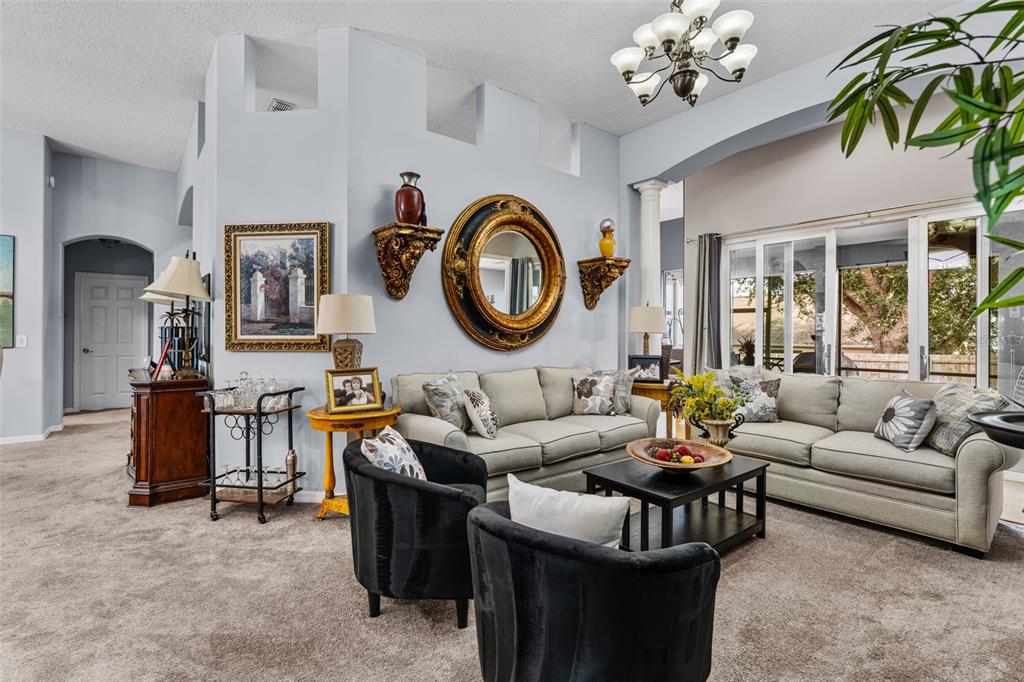 A living room features light gray walls, two beige sofas, black armchairs, and a gold mirror — 1381 SHELTER ROCK ROAD, ORLANDO, FL
