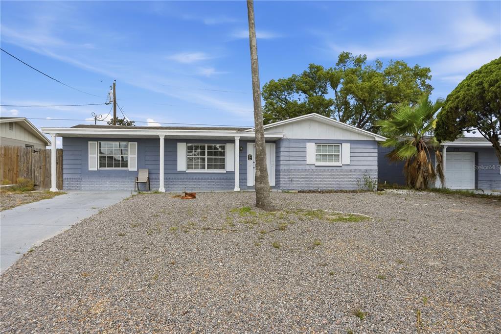 A single-story blue house with a gravel front yard and a palm tree — 3301 ROSEFIELD DRIVE, HOLIDAY, FL