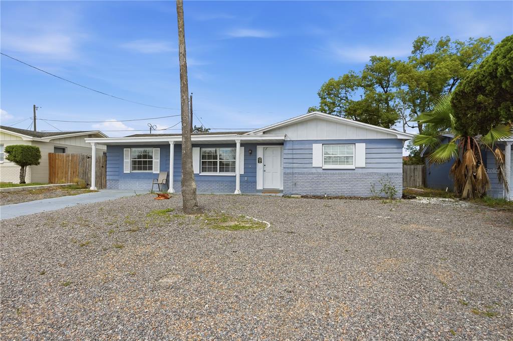 A single-story blue house with a gravel front yard and a palm tree — 3301 ROSEFIELD DRIVE, HOLIDAY, FL