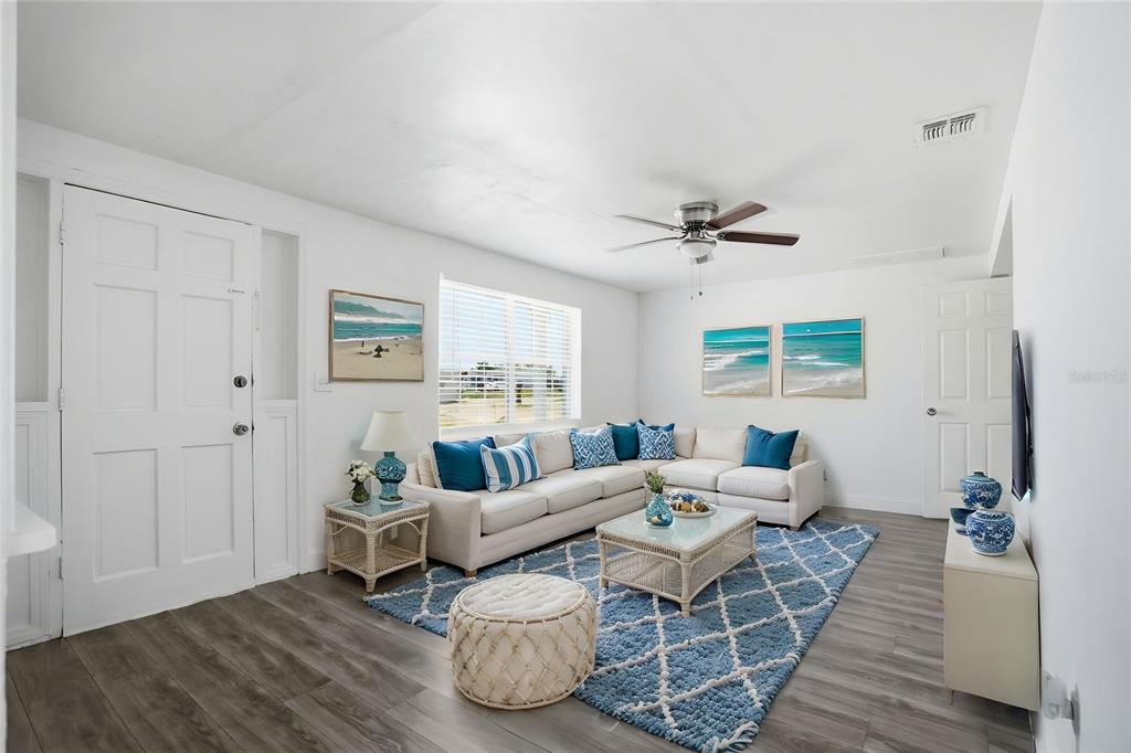 A living room features a white sectional sofa, blue area rug, and wood-look flooring — 3301 ROSEFIELD DRIVE, HOLIDAY, FL