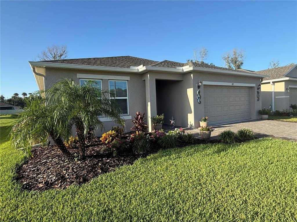 A single-story house with a beige exterior, a two-car garage, and a landscaped front yard — 182 JONES FISH CAMP ROAD, EDGEWATER, FL